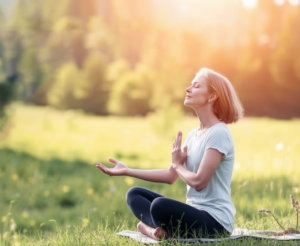 Person meditating in a peaceful outdoor setting to reduce stress